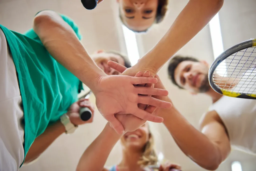 A group of tennis players with their hands in together
