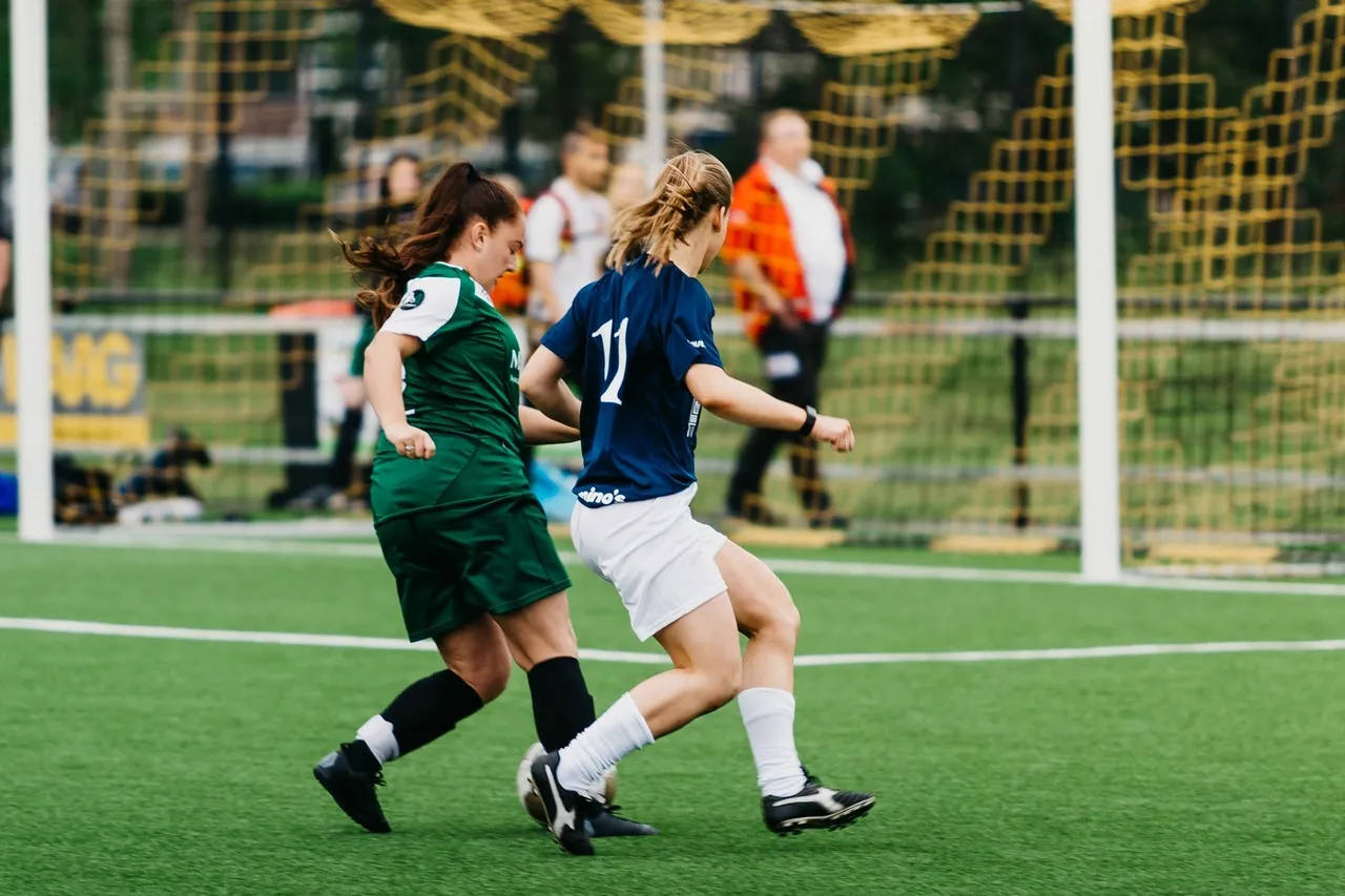 Two female football players Two female football players competing for the ball near the goal
