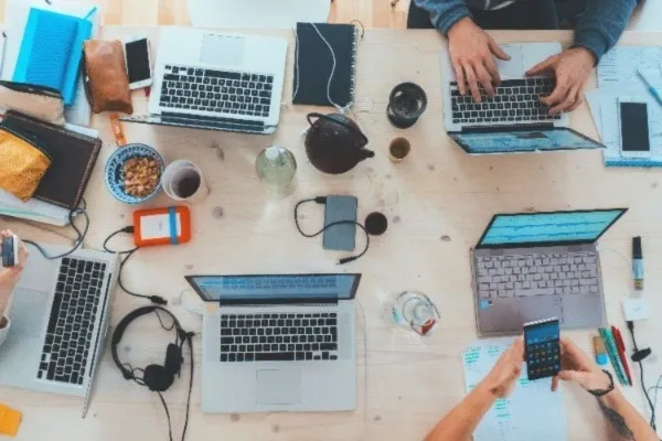 A birds eye view of a group of people working with laptops and phones