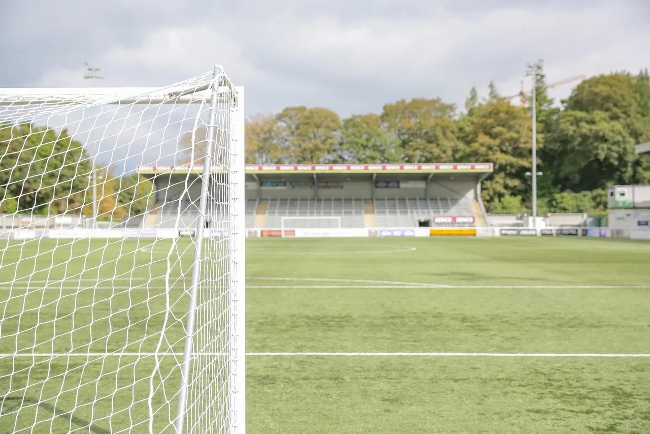 A behind the goal view of a football pitch on a sunny day