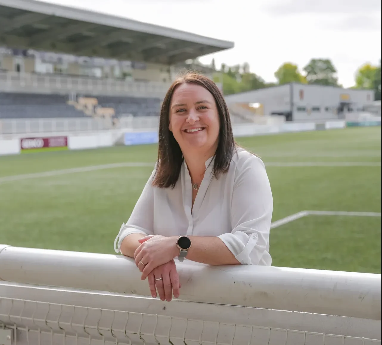 Natalie Doyle smiling whilst leaning on the a football pitch surrounding