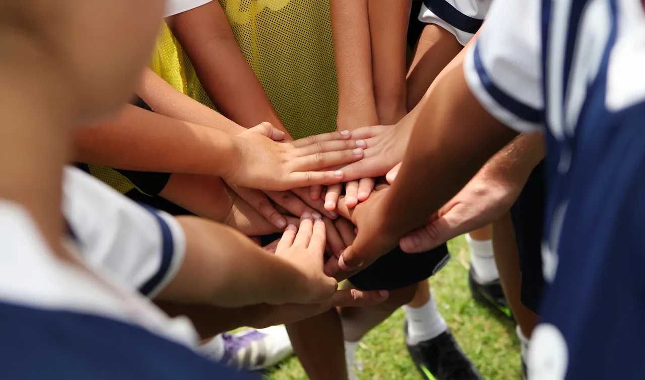 A group of child footballers with their hands in together in a huddle