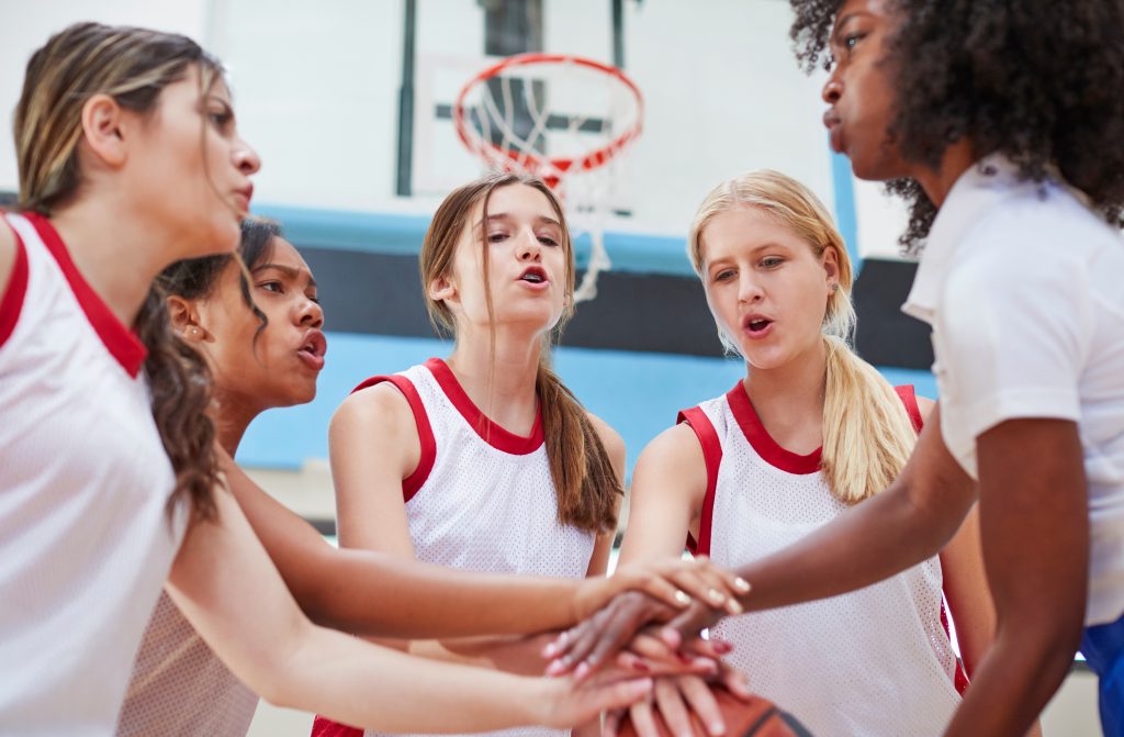 A group of teenage girls in a huddle before the start of a basketball game